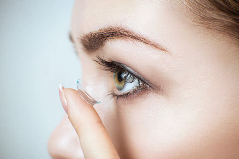 Close up profile of woman placing contact lens on to eye