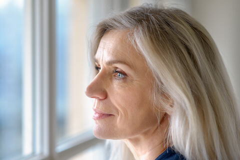 Mature woman looking out window with slight smile