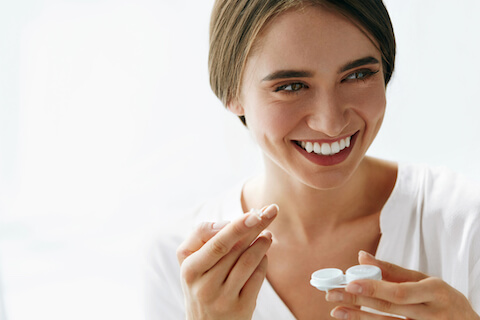 Young woman putting in contact lenses