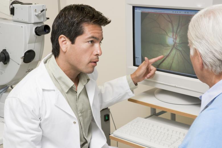 Eye doctor looking at photo of eye on monitor