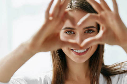 Young woman looking through heart shape made with her fingers
