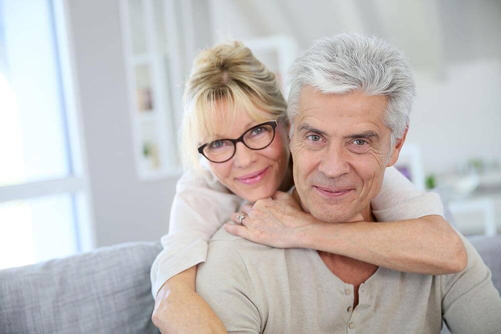 Older couple on couch posing for camera
