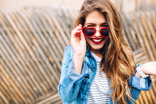 woman smiling while wearing heart sunglasses