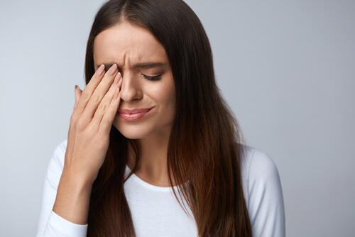 Woman in discomfort covering her eye